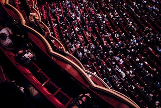 A hall packed full with people sitting.