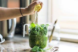 Hand squeezing a lemon into spinach
