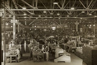 black and white image of workers in a large factory