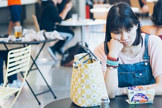 Unhappy woman sitting alone at a lunch table