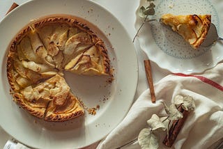 A picture of an apple pie on a plate with a slice cut out