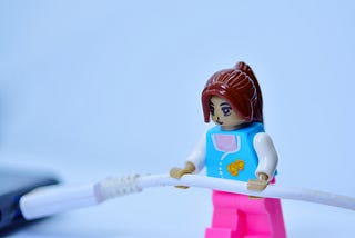 Female lego figure pulling out a laptop power cord