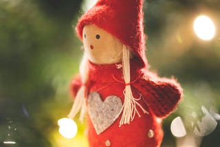 A toy elf hanging on a Christmas tree.