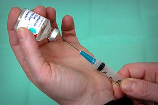A needle entering a bottle containing the flu vaccine.
