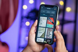 A hand holding a mobile device showcasing digital products