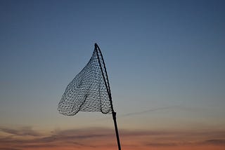 An empty fishing net with the early morning sky in the background.