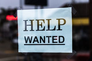 Help Wanted printed sign stuck up in a window