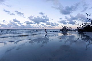 A blue seascape with a solitary girl in the dis