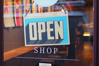 An open shop sign in front of a door