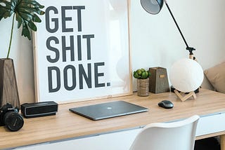 A work desk with a frame that says ‘Get Shit Done’