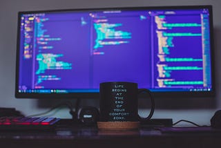 a computer screen and a coffee cup that has the slogan “Life begins at the end of your comfort zone”