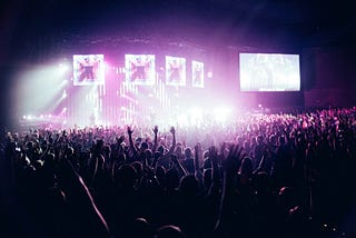 Massive crowd facing a large brightly-lit stage.