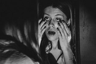 a woman looking her in the mirror tired