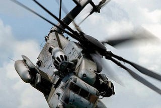 grey helicopter in cloudy sky with helicopter blades in motion; posted on 2024 mickey markoff article on aviation history month