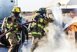 Two firemen fighting a vehicle fire