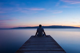 Man sitting in docks looking peacefully at nature.