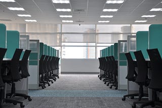 An office space full of empty cubicles, all chairs matching neatly.
