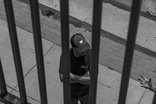 Man standing behind what look like bars