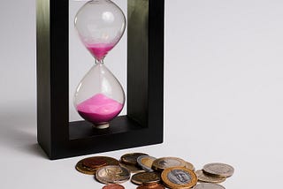 picture of an hour glass representing time, and coins representing money