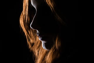 Foto da autoria de Christian Holzinger encontrada no Unsplash. Essa foto foi escolhida para simbolizar a iluminação com luz de fundo, que, nessa fotografia ilumina uma mulher branca com cabelos alaranjados.
