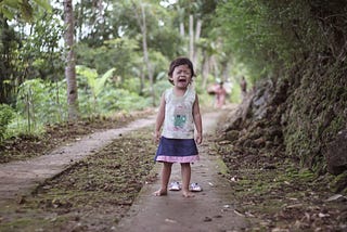 an crying, angry little girl on a path