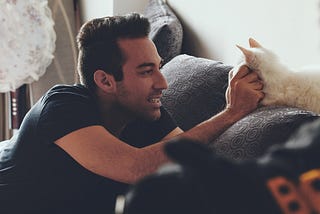 A man petting a cat on a couch
