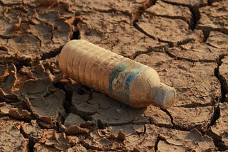 A plastic bottle on broken and cracked soil.
