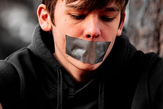 A boy with a piece of tape on its mouth.