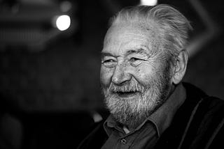 an old man smiling in a black and white picture