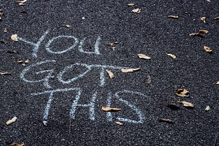 Asphalt with dry leaves and chalk writing. “YOU GOT THIS”