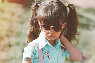 A little girl wearing sunglasses and giving attitude.