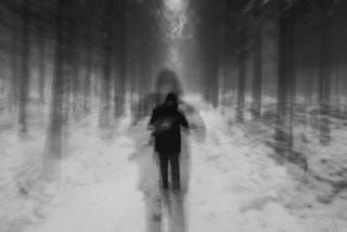 A blurry black and white image of a person in the woods.