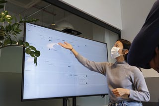 An employee sharing their work on a large display to colleagues.