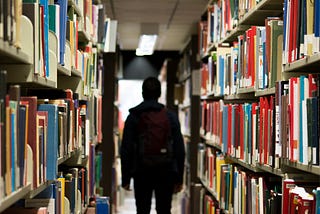 A silhouette of a man standing in the library aisle.