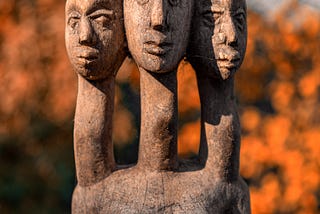 Handmade wooden statue with three heads and one heart. — three parts make a whole in a trinity