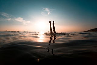 Someone does an underwater handstand with their legs sticking out above the water