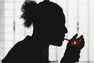 Silhouette of a man lighting a cigarette.