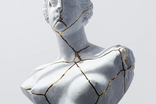 Kiritsugo art: a broken statue put back together with threads of gold, showing where it was cracked.