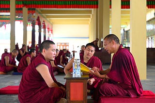 A monk giving the examination on a text he has memorized. The examiner (right) chooses passages at random and the student (left) has to finish the passage from memory.