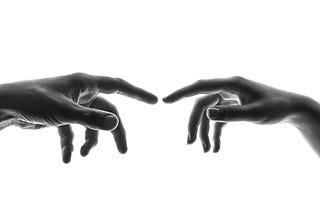 Two hands with pointers held up, nearly touch.
