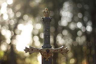 The hilt of a decorated sword sticking out of the ground.