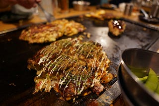 Okonomiyaki frying on a hotplate.