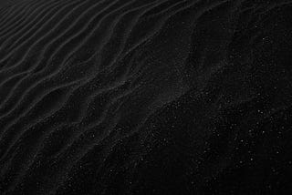 this black rippling sand with specks of white, comments on the idea that nothing is greater than nothing