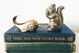 Brass book ends of a whale and squirrel seating on two vintage books
