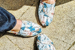 Three feet, wearing the same shoes with a Disney Princesses pattern