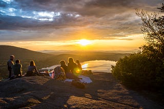 six people sitting in a semi-circle in nature