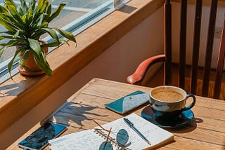 experts take on editing. A writing notebook, coffee cup on a small writing desk. It is a roadside cafe.