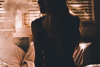 Silhouette of a girl sitting on a bed while smoking