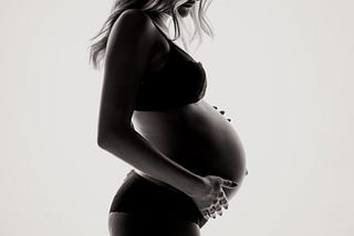 A pregnant woman in backlight.