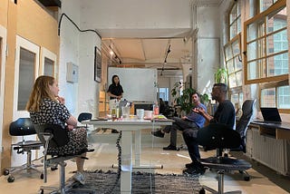 Four people sitting around a table in an office space having a discussion.